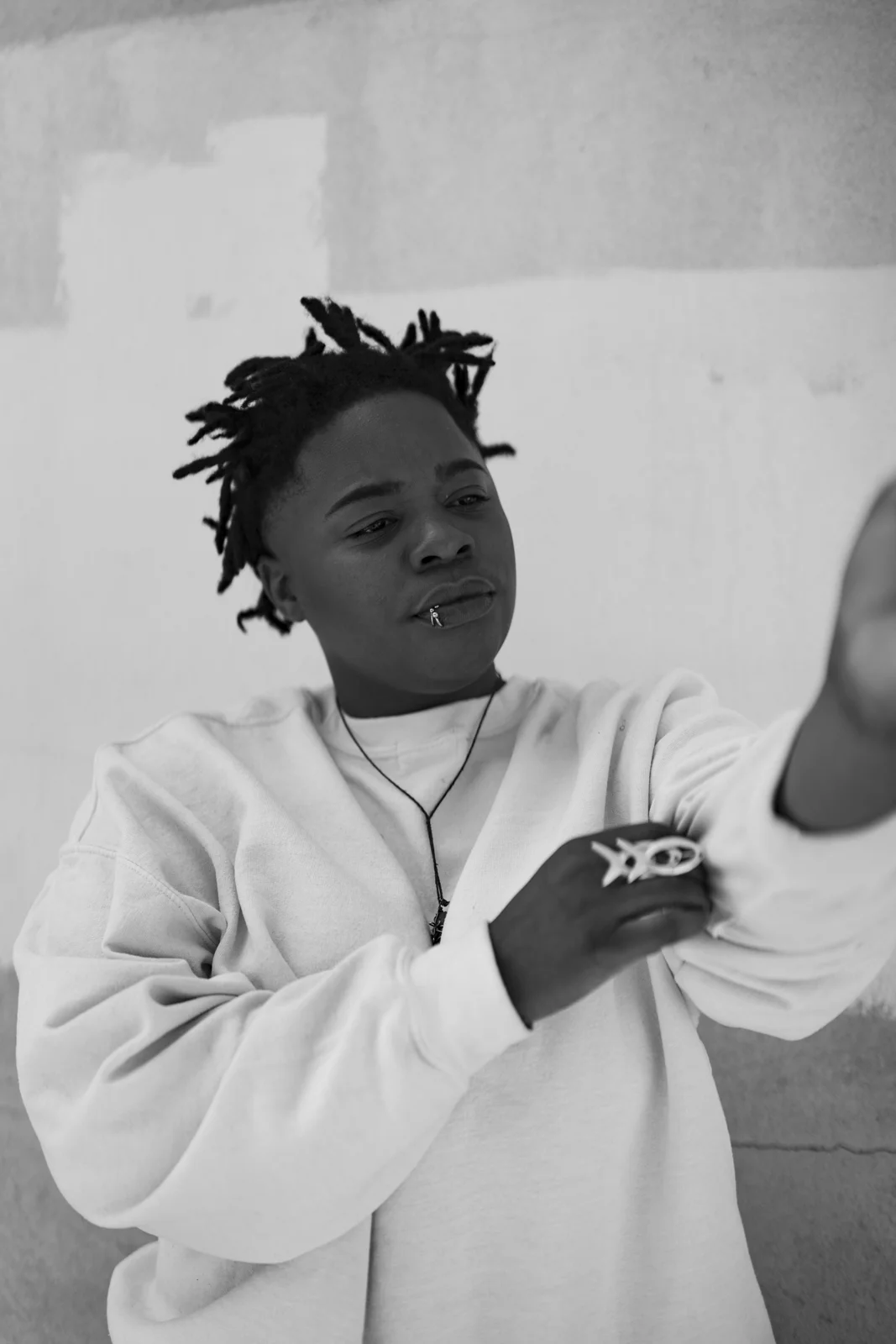 Speech Debelle in black and white, wearing a white sweatshirt and a fish ring