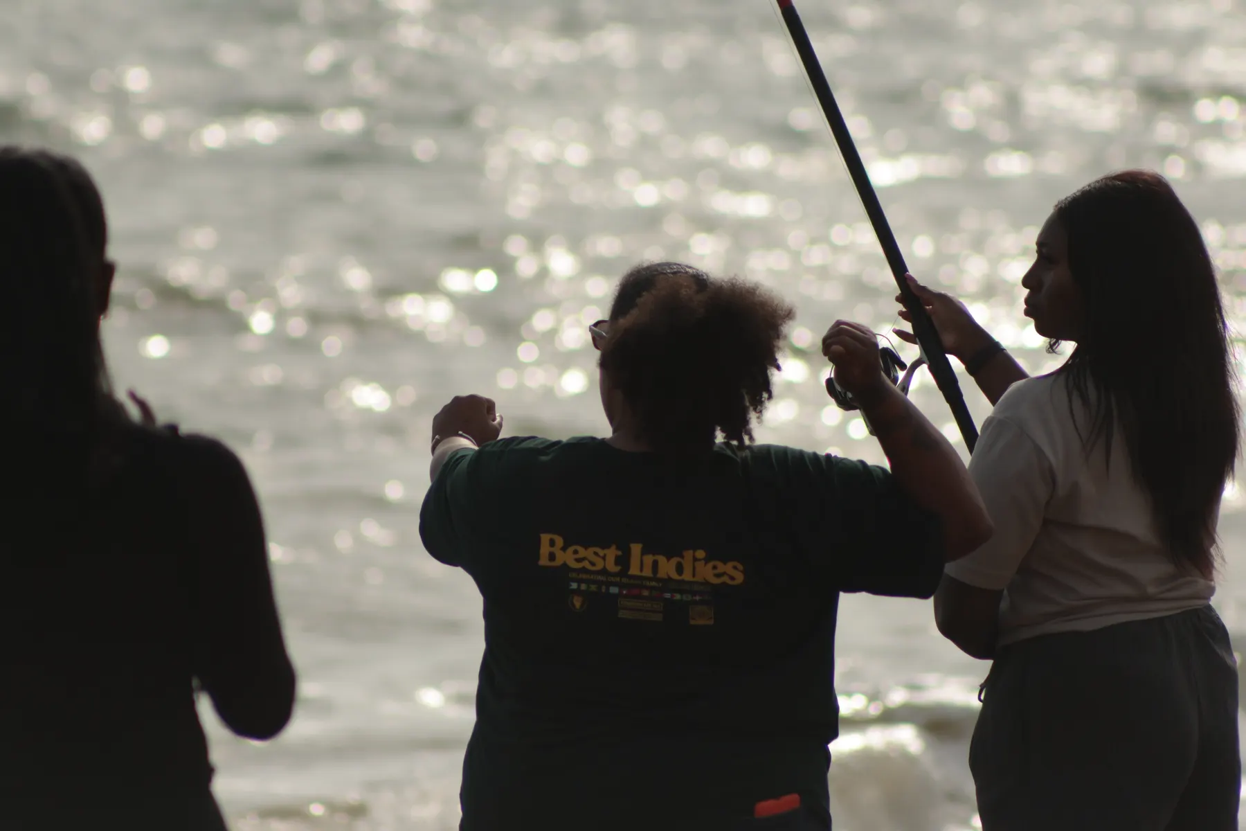 People fishing together beside sunlit water